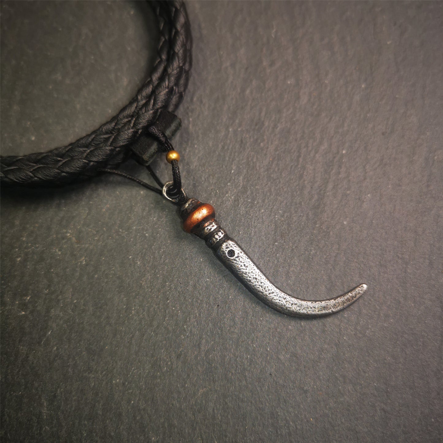 This wolf tooth pendant is made by Tibetan craftsmen and come from Hepo Town, Baiyu County, the birthplace of the famous Tibetan handicrafts. It's made of cold iron and inlaid copper,the body is black color,length is 1.77 inches. You can make it a necklace or mala pendant, or keychain.