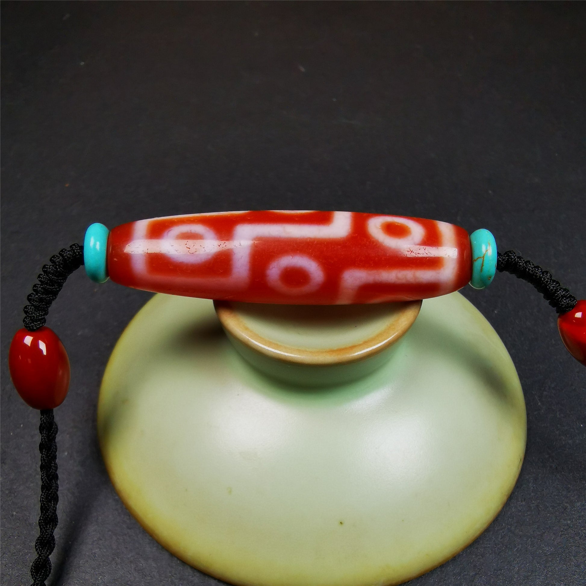 This fire agate 9 eyes dzi necklace was hand-woven by Tibetans from Baiyu County, the main bead is a fire agate 9 eyes dzi, paired with 2 turquoise beads and 2 red agate beads,about 30 years old. The length of the necklace can be adjusted, the maximum circumference is about 60cm.