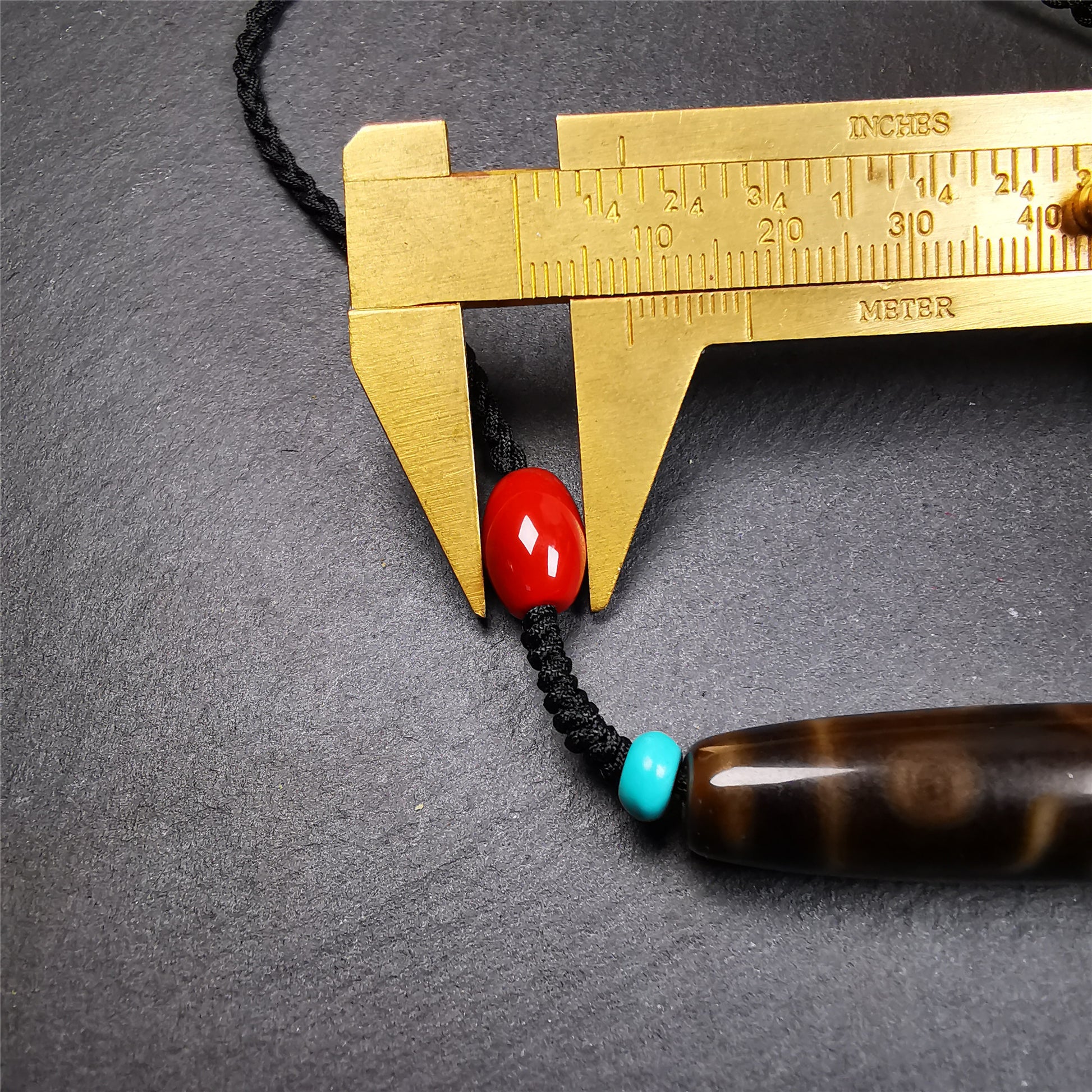 This necklace was hand-woven by Tibetans from Baiyu County, the main bead is a brown color 9 eyes dzi, paired with 2 turquoise beads and 2 red agate beads,about 30 years old. The length of the necklace can be adjusted, the maximum circumference is about 60cm.