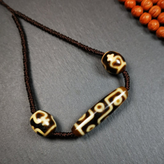 This necklace was hand-woven by Tibetans from Baiyu County, the main bead is a 9-eye dzi, paired with 2 treasure vase dalo dzi beads,about 30 years old. It can be worn not only as a fashionable accessory but also holds cultural and religious significance.Gandhanra Vintage Tibetan 9 Eyed Dzi +Treasure Vase Dalo Bead Necklace