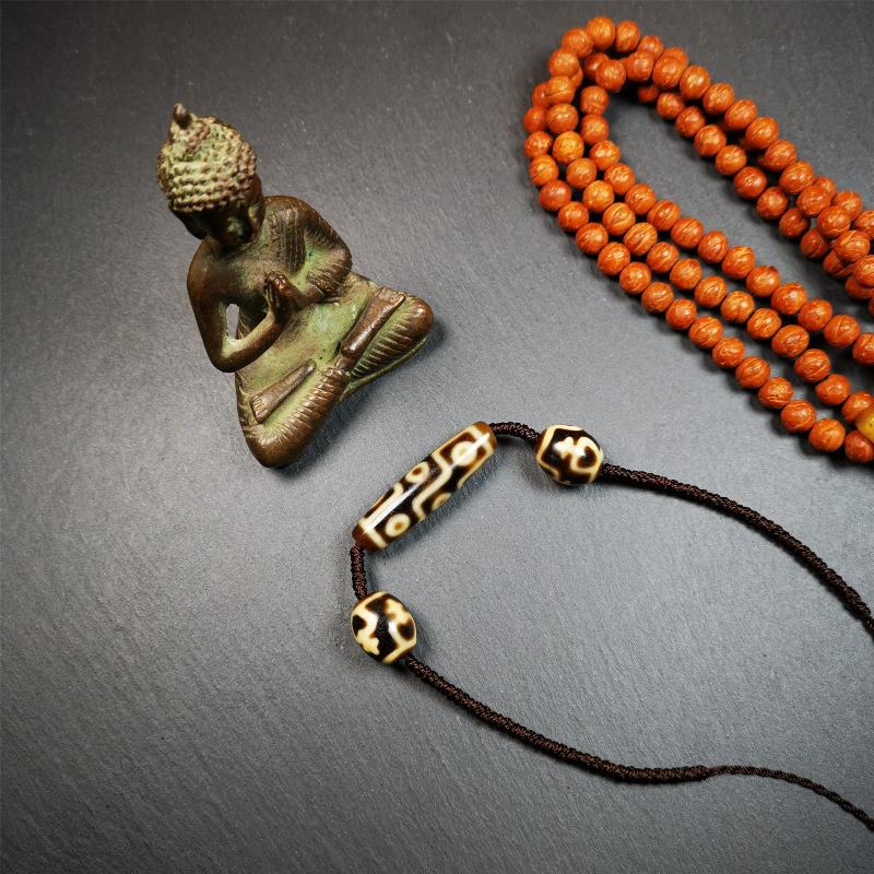 This necklace was hand-woven by Tibetans from Baiyu County, the main bead is a 9-eye dzi, paired with 2 treasure vase dalo dzi beads,about 30 years old. It can be worn not only as a fashionable accessory but also holds cultural and religious significance.