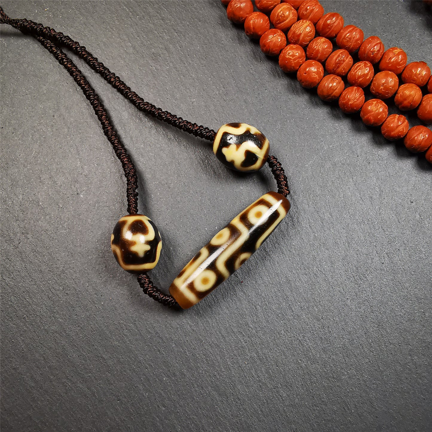 This necklace was hand-woven by Tibetans from Baiyu County, the main bead is a 9-eye dzi, paired with 2 treasure vase dalo dzi beads,about 30 years old. It can be worn not only as a fashionable accessory but also holds cultural and religious significance.