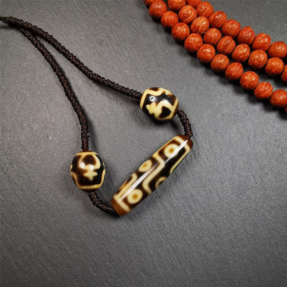 This necklace was hand-woven by Tibetans from Baiyu County, the main bead is a 9-eye dzi, paired with 2 treasure vase dalo dzi beads,about 30 years old. It can be worn not only as a fashionable accessory but also holds cultural and religious significance.