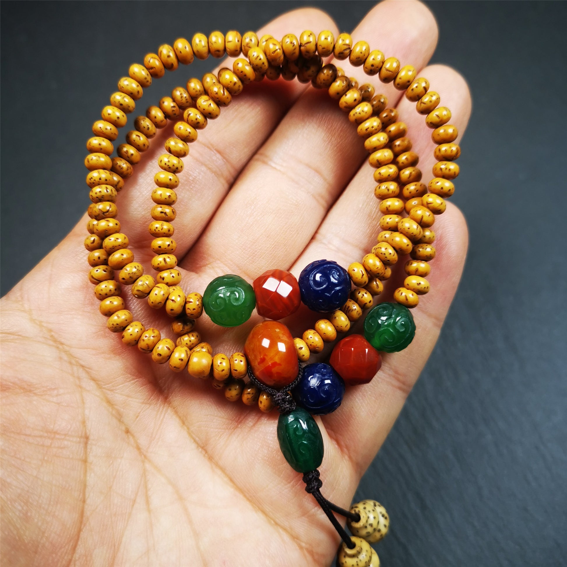 This mala is made by Tibetan craftsmen. It is composed of 108 lotus seed beads(5mm / 0.2"),perimeter is about 56cm,22inches.equipped with red, blue and green agates, very elegant.  It is worn with an elastic cord, so it fits the wrist very well, suitable for women to use as a bracelet mala
