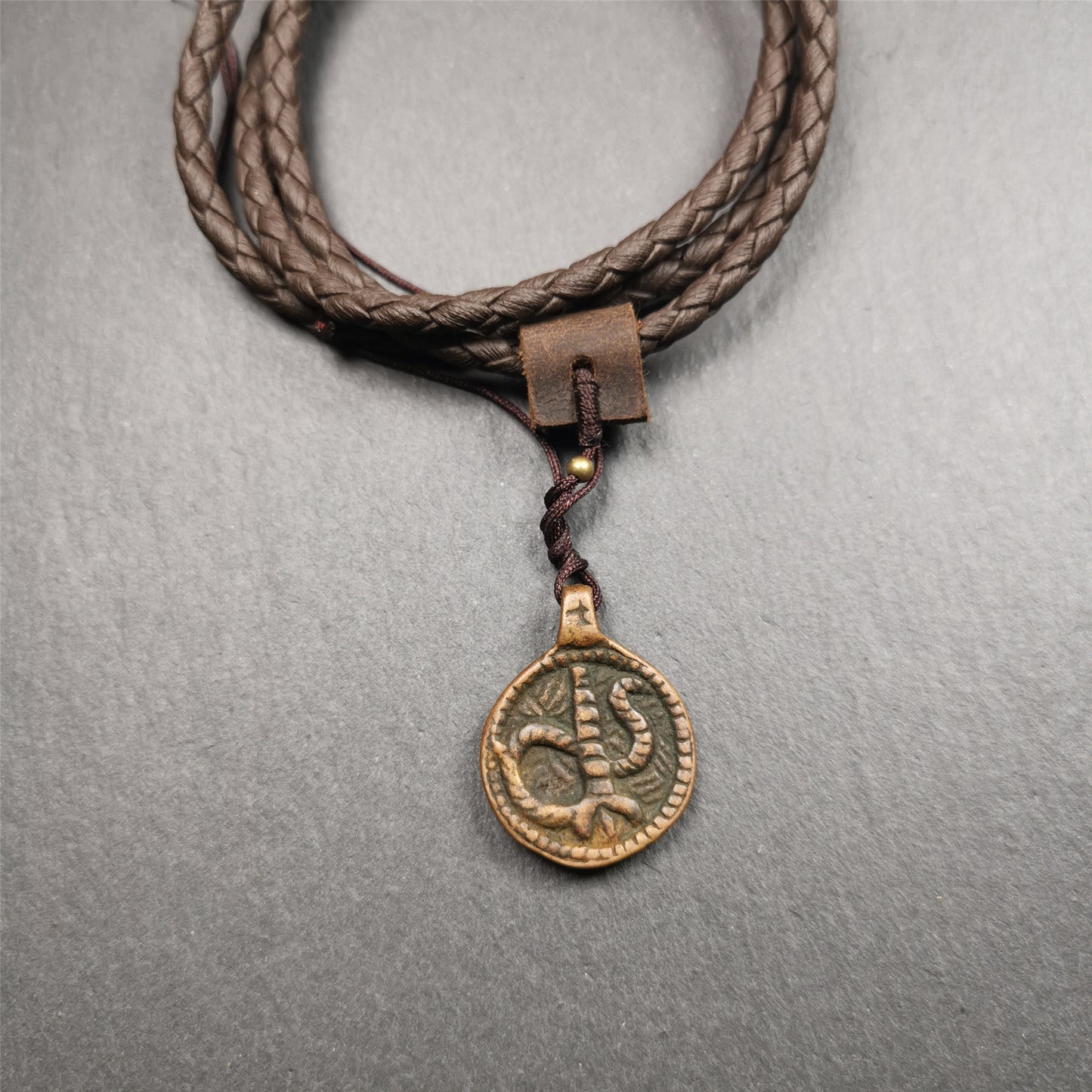 These amulet were  handmade by Tibetan craftsmen from Tibet in 1990's. It's made of copper/brass,brown/yellow color,diameter is 0.83 inch,comes with a leather cord. You can make it into a necklace,or bag hanging