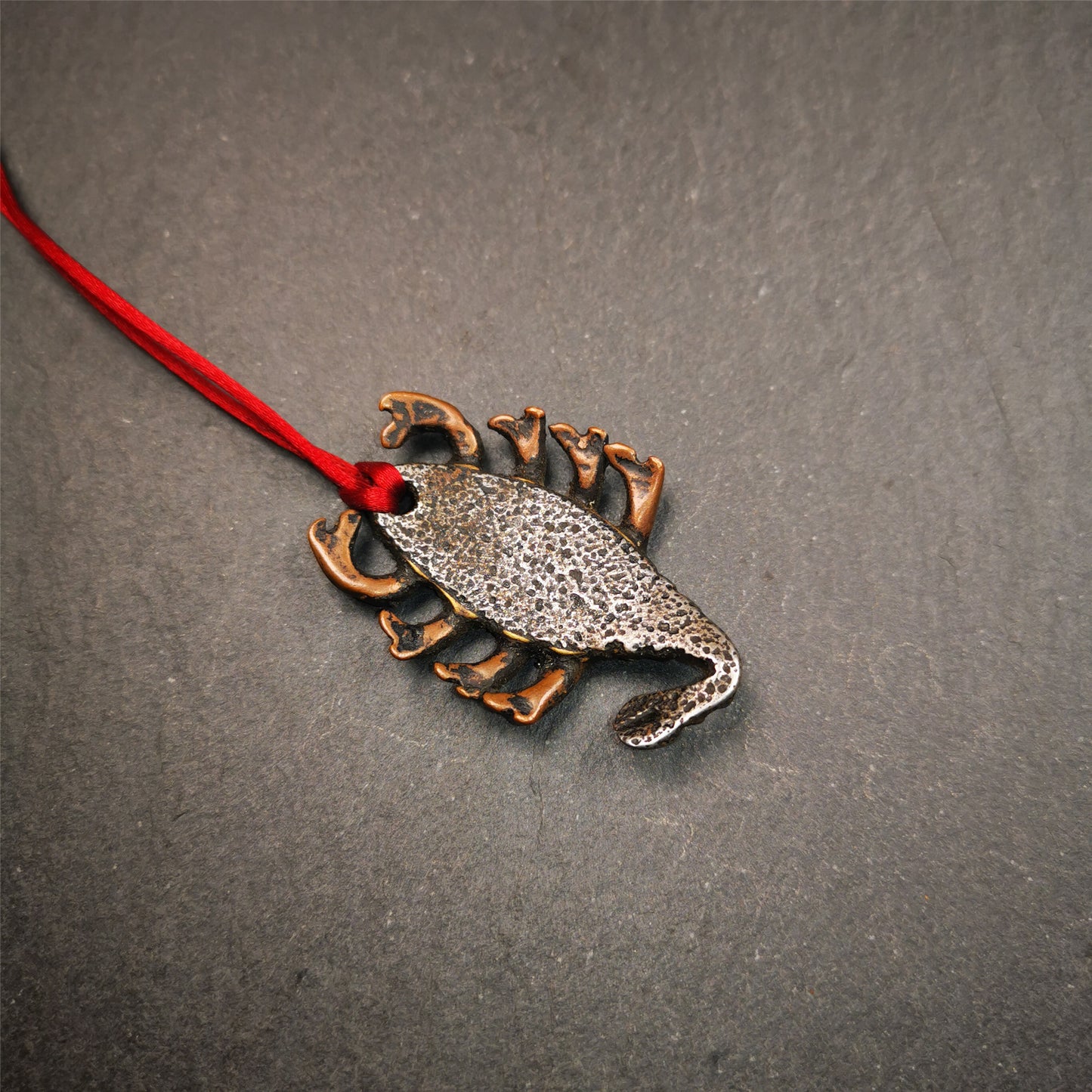This scorpion amulet is made by Tibetan craftsmen in Hepo Township, Baiyu County, the birthplace of the famous Tibetan handicrafts. It is made of cold iron and copper,black color, size is 1.6 × 1.2 inches.The body is cold iron,and the legs are copper wire. You can make it into a necklace, or a keychain, or just put it in your shrine.