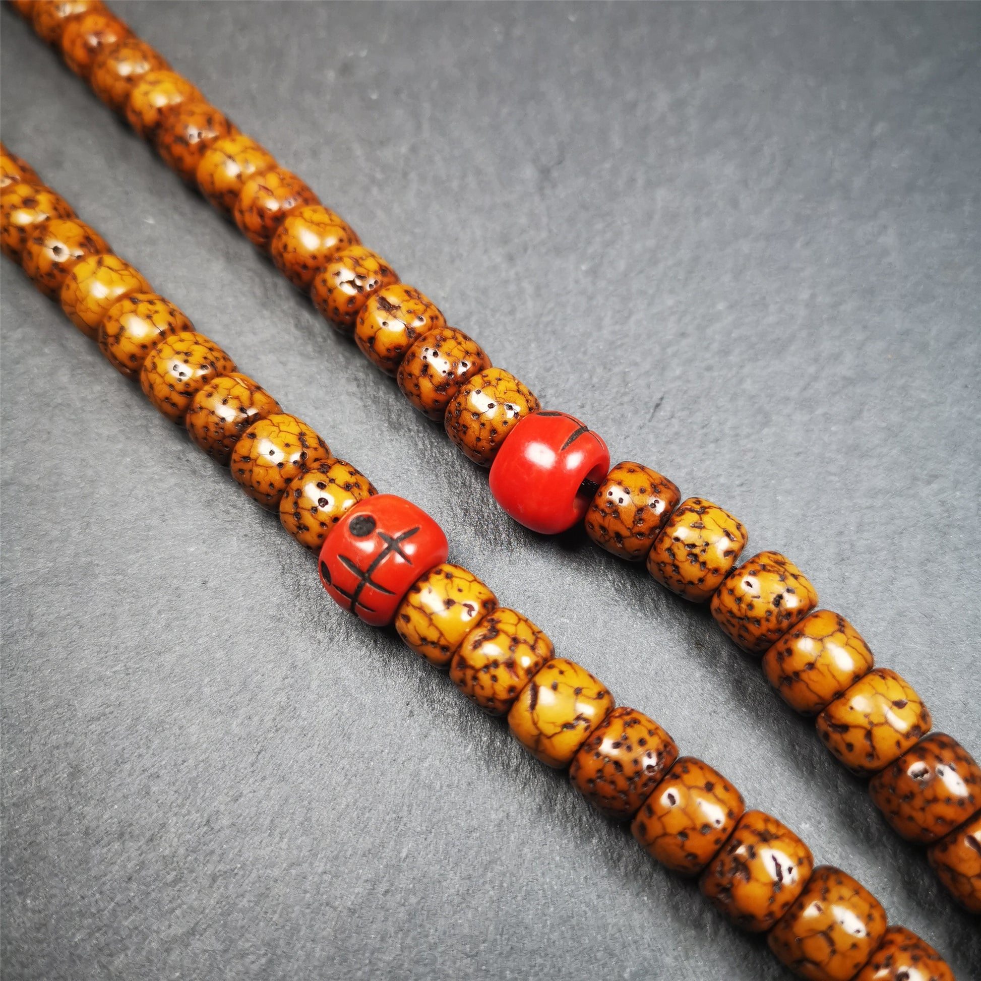 These marker beads were handmade by Tibetan craftsmen and come from Hepo Town, Baiyu County, the birthplace of the famous Tibetan handicrafts. It is made of plastic,carved skull pattern,red color,size is 0.4" × 0.3".