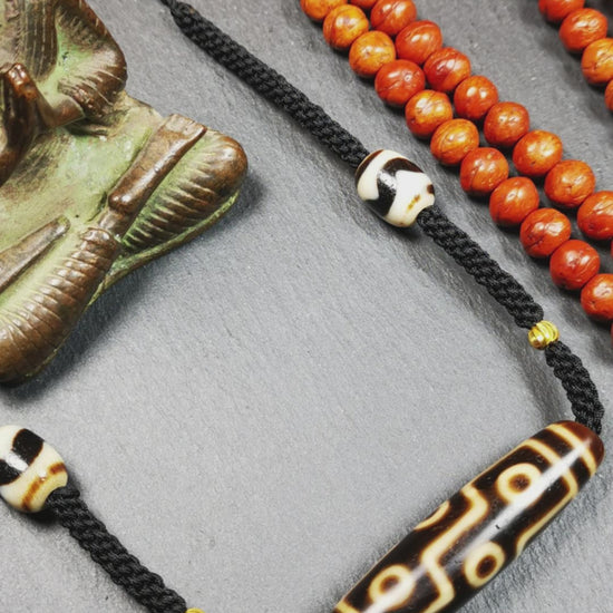 This necklace was hand-woven by Tibetans from Baiyu County, the main bead is a 9 eyed  dzi bead, paired with 2 small tiger tooth dzi beads,about 30 years old. It can be worn as a fashionable accessory,holds cultural and religious significance.