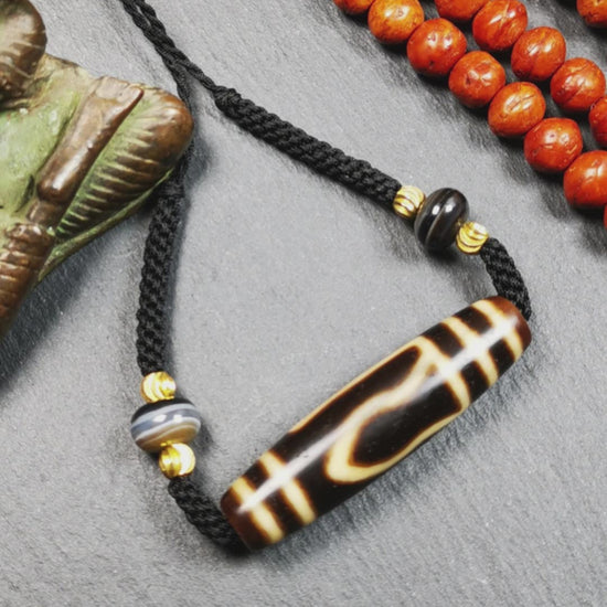 This necklace was hand-woven by Tibetans from Baiyu County, the main bead is a mountain eye dzi bead, paired with 2 small stripe dzi beads,about 30 years old. It can be worn not only as a fashionable accessory but also holds cultural and religious significance.