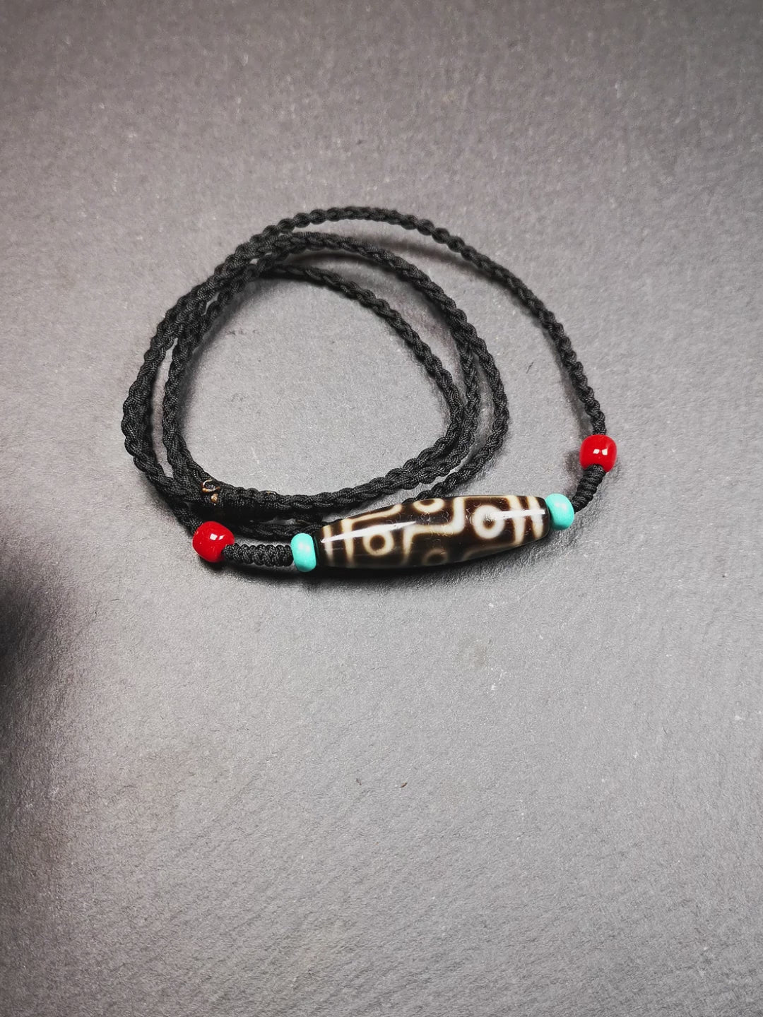 This 9 eyes dzi bead was collected from gerze Tibet,about 40 years old. The necklace was hand-woven by Tibetans from Baiyu County, the main bead is a brown color 9 eyes dzi, paired with 2 turquoise beads and 2 red agate beads.