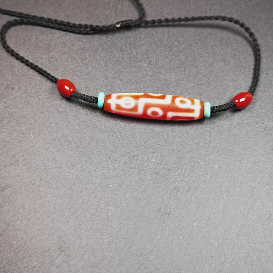 This fire agate 9 eyes dzi necklace was hand-woven by Tibetans from Baiyu County, the main bead is a fire agate 9 eyes dzi, paired with 2 turquoise beads and 2 red agate beads,about 30 years old. The length of the necklace can be adjusted, the maximum circumference is about 60cm.